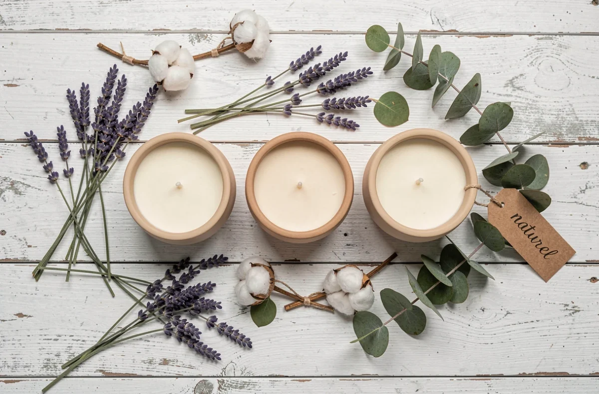 Bougies parfumées biologiques en céramique entourées de plantes séchées et de lavande sur une table en bois